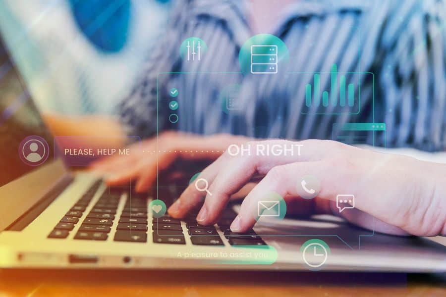 Close-up of hands typing on a laptop keyboard with digital icons overlayed